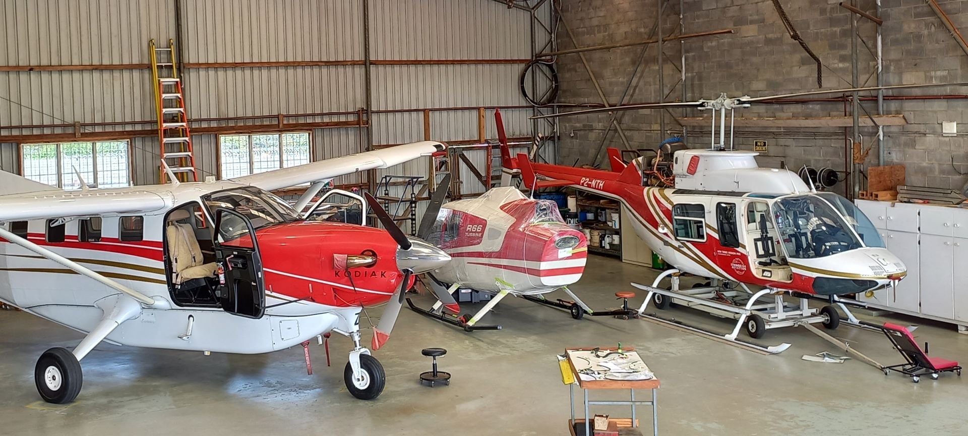 Det første R66-helikopteret, fortsatt innpakket, i hangaren i Papua Ny-Guinea i 2022, mellom et Kodiak-fly og et eldre helikopter