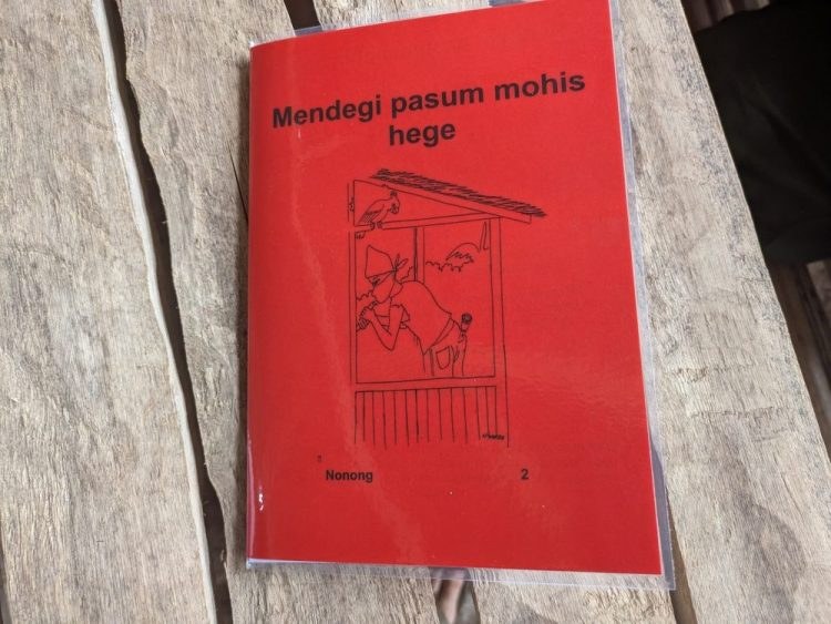 Et rødt lesehefte på kovol-språket